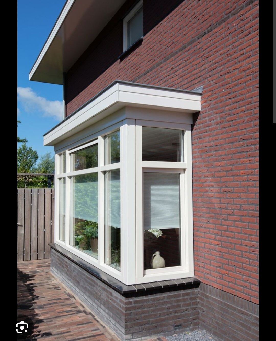 Volledig geschilderde witte houten erker met glasvlakken aan een bakstenen woning — kozijnenonderhoud en buitenschilderwerk door Houtschilderwerk Limmen in Heiloo en omgeving